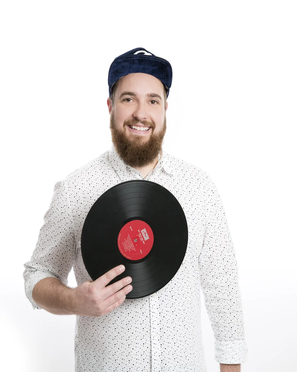 Sune Træben med kasket holder en vinylplade i hånden og smiler.